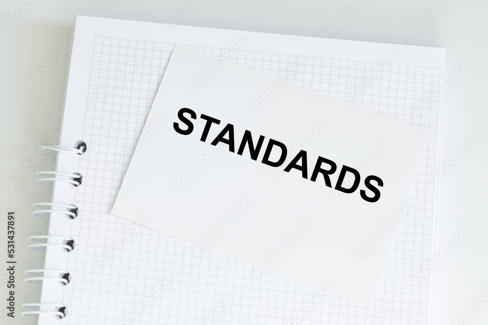 STANDARDS inscription on a card on a notebook on a light background, business concept STANDARDS inscription on a card on a notebook on a light background, business concept