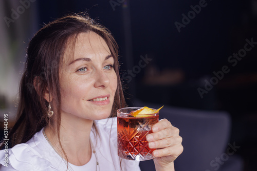 a girl drinks a negroni cocktail on the terrace of a modern restaurant
