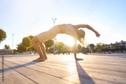 Young sporty woman training in outdoor, working out at animal flow style, making crab position. 