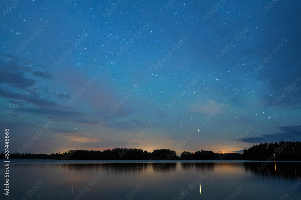 Night landscape under starry sky, stars reflecting from calm water surface, distant thunder in the horizon.