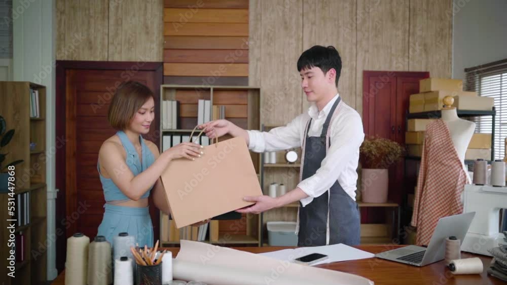 Young asian sales man gives shopping bag with purchased merchandise and clothes to woman customer, Beautiful female buying dress in tailor-made clothing store and pay by credit card.
Young asian sales man gives shopping bag with purchased merchandise and clothes to woman customer, Beautiful female buying dress in tailor-made clothing store and pay by credit card.