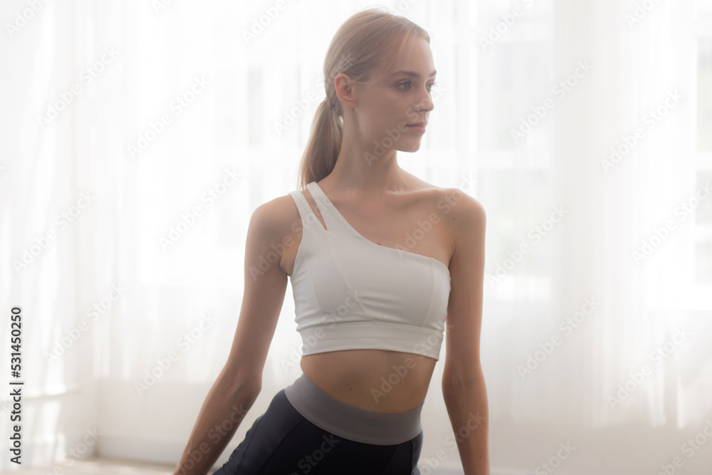 Young woman practicing exercise or yoga on mat while workout with stretching leg at home, woman having motivation and determined with exercise, one person, lifestyles and sport concept.