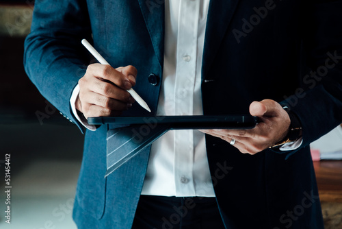 Close up businessman holding pen and tablet for work in office.