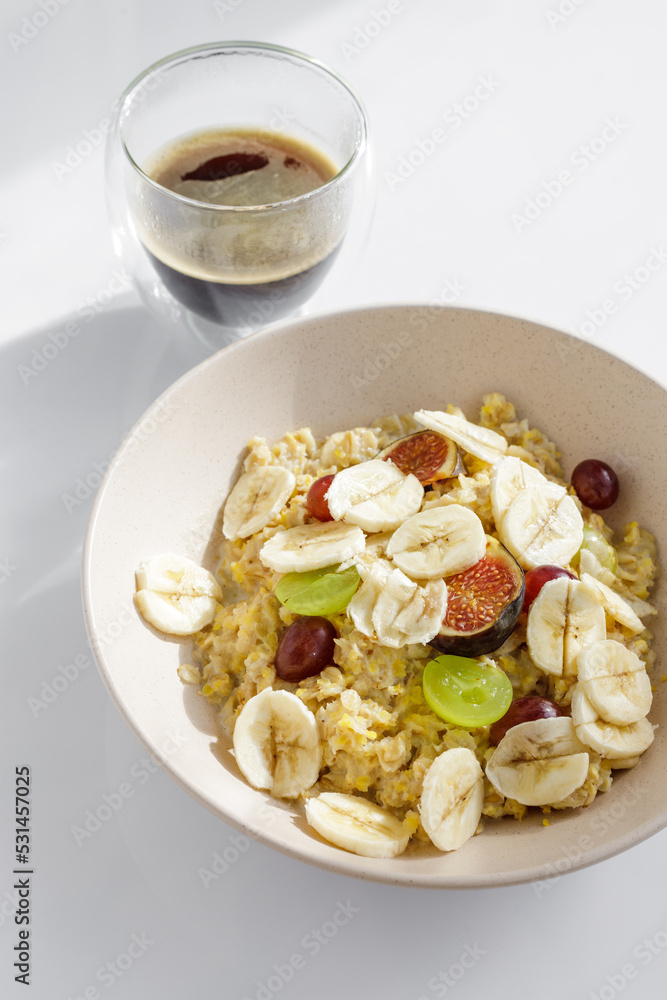 Top view of morning meal on white background. Oatmeal with fruit and cup of coffee