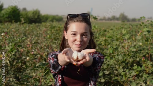 A young girl collects cotton on her knees . A teenager enjoys a cotton flower on a farm.