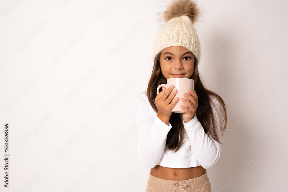 A little girl holds a cup with a warm drink in the cold season. Winter clothes on the child. A little girl holds a cup with a warm drink in the cold season. Winter clothes on the child.