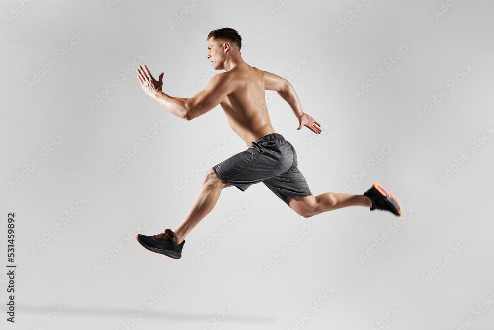 Confident muscular man with perfect body running against white background