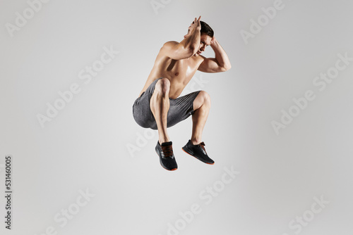 Fototapeta Naklejka Na Ścianę i Meble -  Young fit man with perfect body jumping against white background