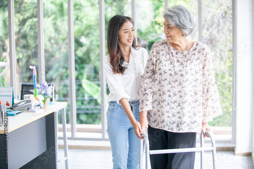 Asian girl assisting elderly woman trying to walk at home, health care, senior therapy patient at home concept.