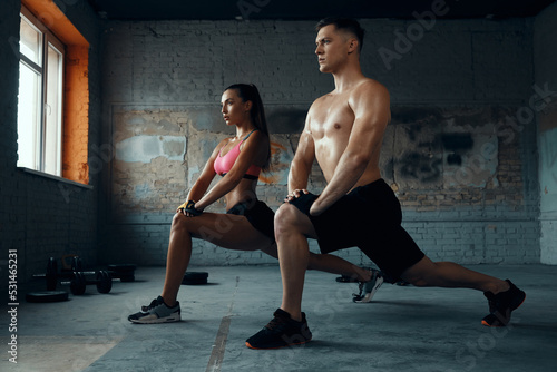 Confident fit couple doing stretching exercises in gym together