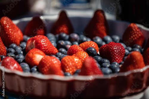 Blueberry and strawberries fresh fruit bowl. Selective focus. Strong contrast. Background.