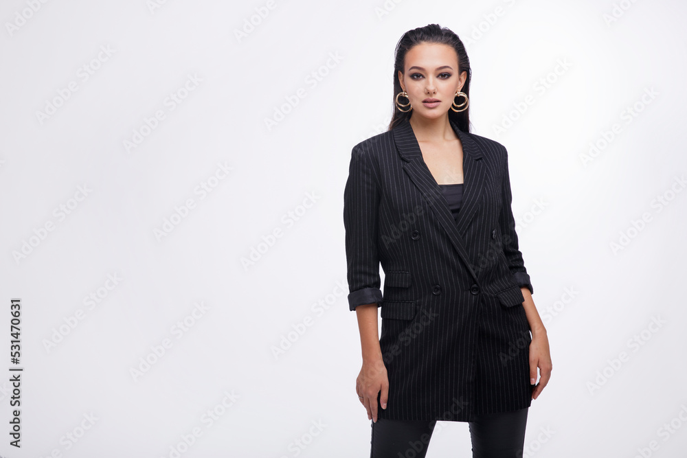 Fashion photo of a beautiful elegant young woman in a pretty black jacket, leather pants, boots, posing over white background. The hair is gathered back, dark brunette. Studio Shot Fashion photo of a beautiful elegant young woman in a pretty black jacket, leather pants, boots, posing over white background. The hair is gathered back, dark brunette. Studio Shot