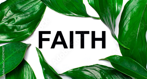 Against the background of green natural leaves, a white card with the text FAITH