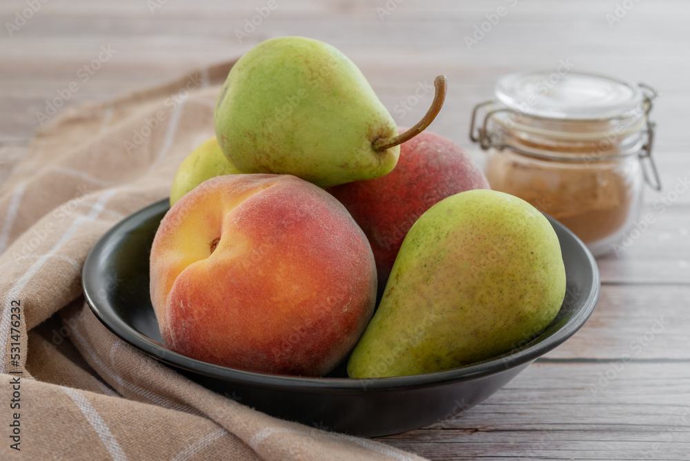 Still life with pears and peaches in a black bowl on a wooden table. Still life with pears and peaches in a black bowl on a wooden table.