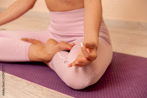Middle aged woman looks good, practicing yoga, fitness, sports, training, woman doing exercises. She is wearing a pink top and leggings. The concept of grace and beauty of the body