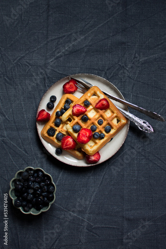 Traditional belgian waffles with fresh berries on dark background