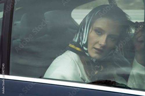 Beautiful woman on the back seat of a car looking out of the window.