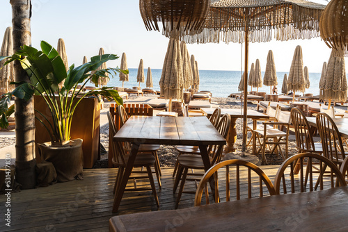 Tables in a cozy beach cafe in Greece early in the morning before opening without visitors
