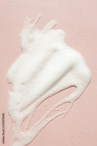 Facial foam texture from soap, face cleansing mousse bubbles on pink background photo