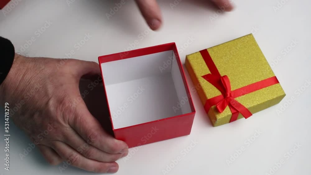 Hands open a gift box and put a present in it. A Christmas concept. Hands open a gift box and put a present in it. A Christmas concept.