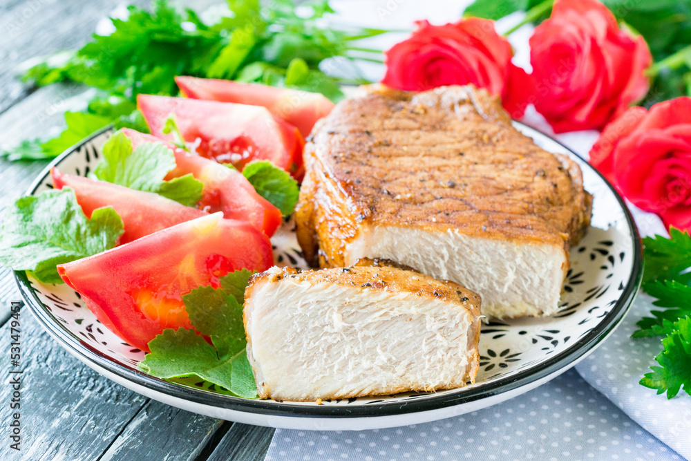 Steak of pork baked in the oven on a plate on a wooden background Steak of pork baked in the oven on a plate on a wooden background
