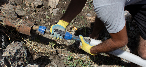 Plumber connects a water pipe in a trench