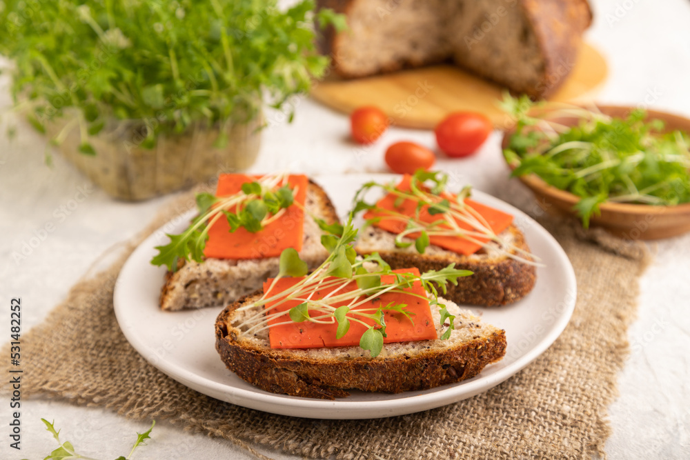 Grain bread sandwiches with red tomato cheese and microgreen on gray, side view, selective focus.