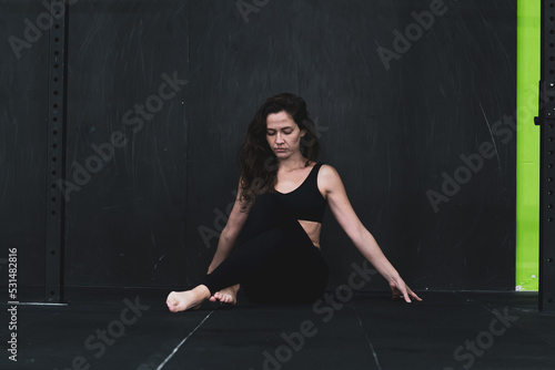 Young woman meditates, doing yoga poses and asana. Fitness girl enjoying yoga indoors. A yoga gymnast girl on a dark background. Black on Black 
