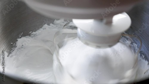 Whipping cream in a mixer. The planetary mixer beats the cream for the cake.
