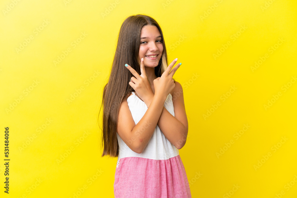 Little caucasian girl isolated on yellow background smiling and showing victory sign Little caucasian girl isolated on yellow background smiling and showing victory sign