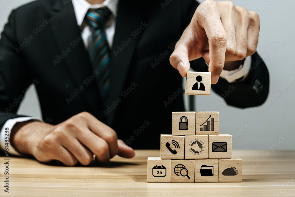 Business Strategy. businessman investor hand arranging wood block with business finance icon on desk, business management, team leader, company growth, market trend, finance, business start up concept Business Strategy. businessman investor hand arranging wood block with business finance icon on desk, business management, team leader, company growth, market trend, finance, business start up concept