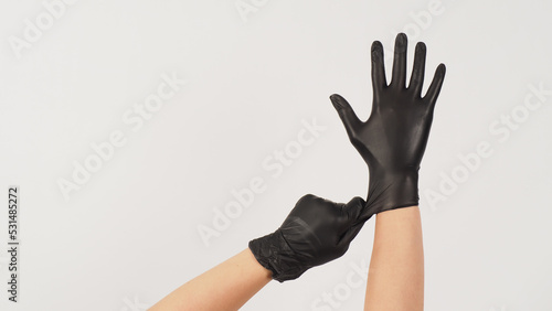 Konstfotografi Hands is pulling black latex gloves on white background.