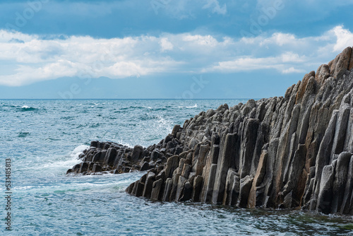 rocky seashore formed by columnar basalt against the surf, coastal landscape of Kunashir Island photo
