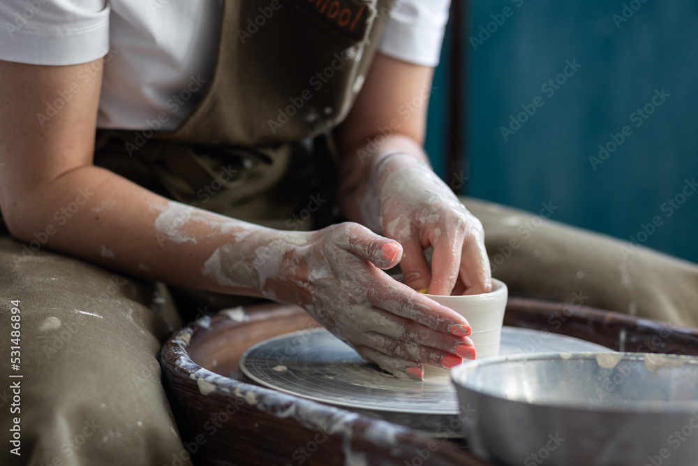 Woman doing pottery on the potter wheel on the workshop Woman doing pottery on the potter wheel on the workshop
