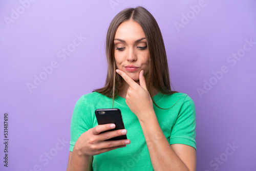 Young caucasian woman isolated on purple background thinking and sending a message
