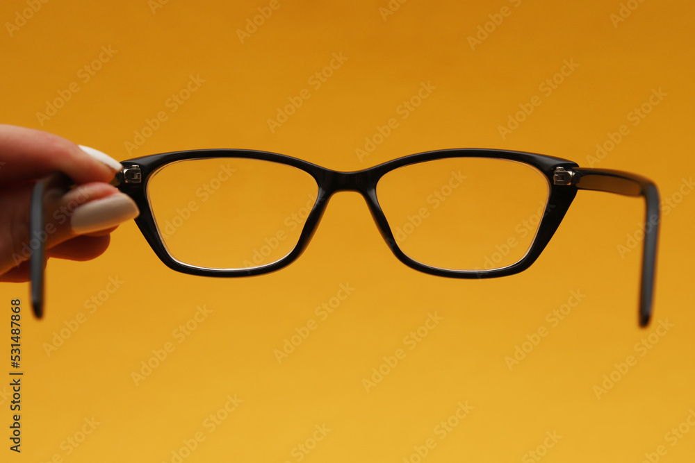 Glasses with diopters in a black frame on an orange background. Shallow depth of field Glasses with diopters in a black frame on an orange background. Shallow depth of field