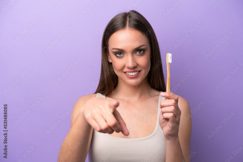 Young caucasian woman brushing teeth isolated on purple background points finger at you with a confident expression Young caucasian woman brushing teeth isolated on purple background points finger at you with a confident expression