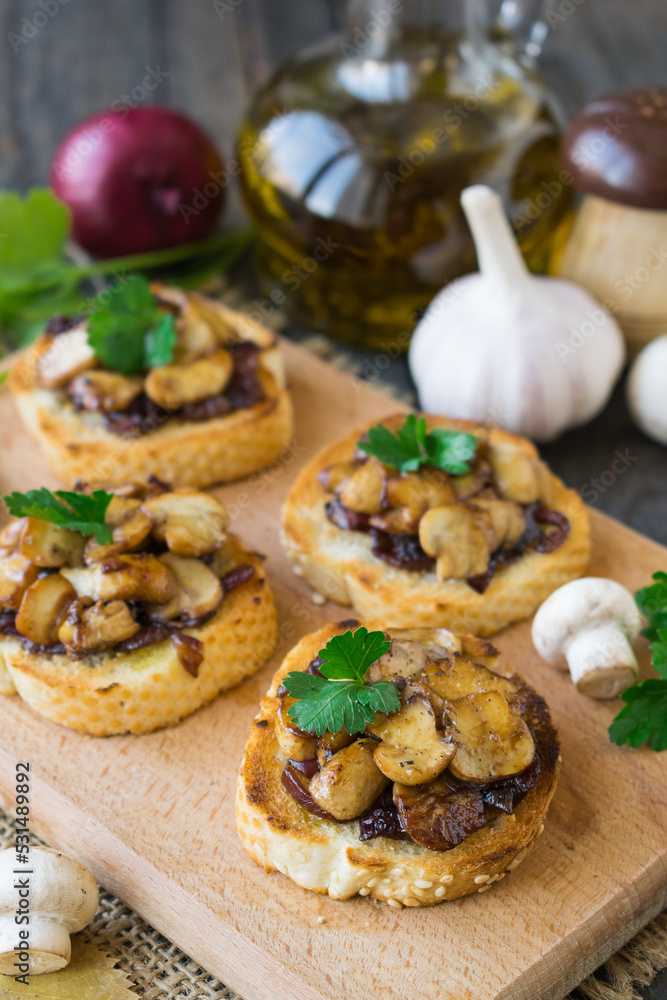 Italian bruschetta with champignons and caramelized red onions on a wooden background. Selective focus