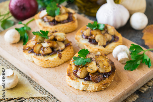 Italian bruschetta with champignons and caramelized red onions on a wooden background. Selective focus