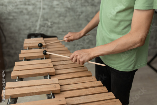 Hands of a young musician playing sticks on a wooden musical instrument xylophone, close-up, selective focus photo