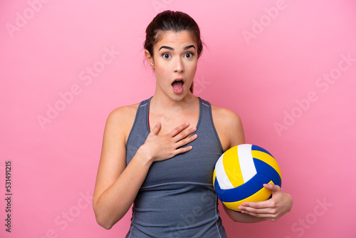 Young Brazilian woman playing volleyball isolated on pink background surprised and shocked while looking right