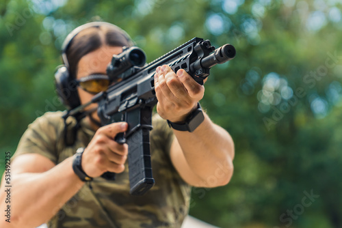 man holding a black rifle to target at the shooting range, outdoors. High quality photo