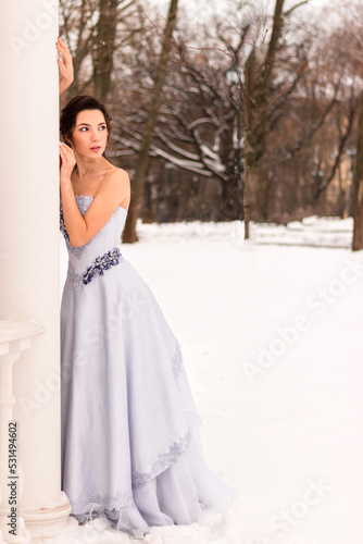 Beautiful woman in a luxurious blue fairy-tale dress in a snowy forest