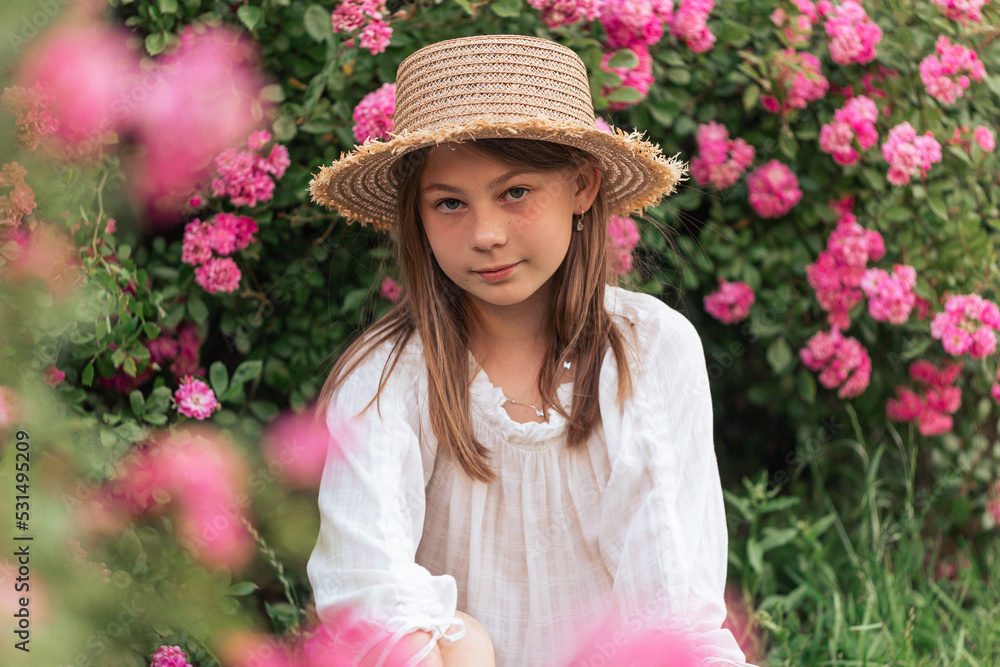 Fototapeta premium portrait of a beautiful girl among pink roses outside