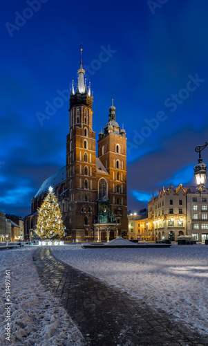 St Mary's church on snow covered Main Square in winter Krakow, illuminated in the night.