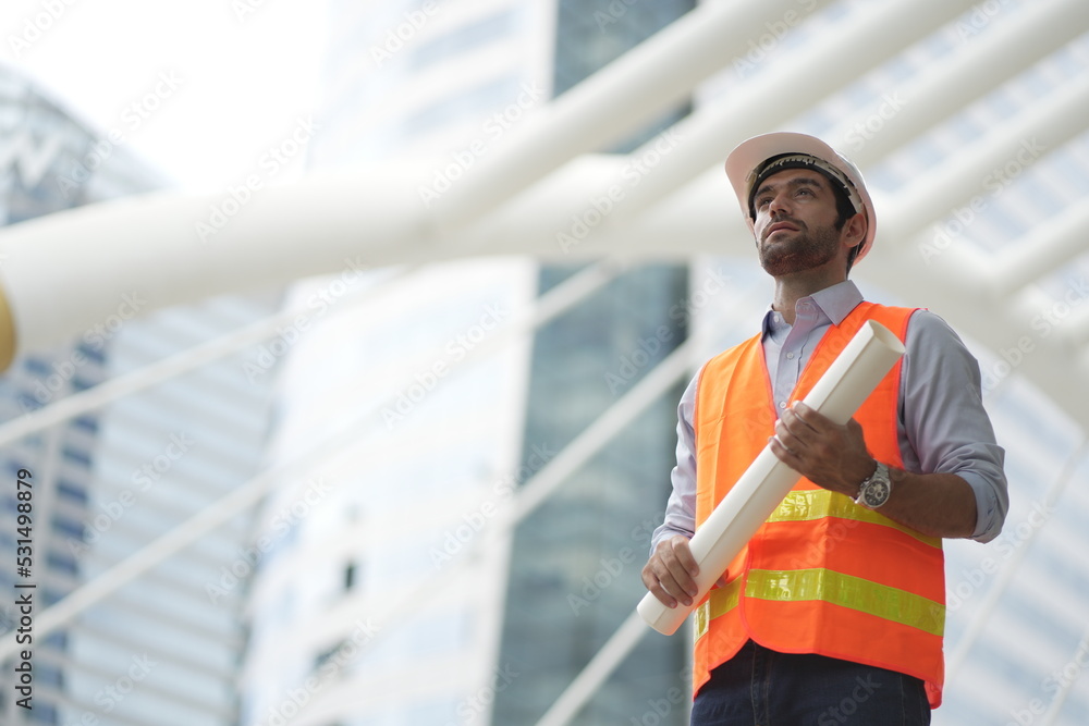 Architect or engineer with blueprints. Cauacsian Engineer checking plan on construction site. modern structure. helmet and blueprints paper. Architect or engineer with blueprints. Cauacsian Engineer checking plan on construction site. modern structure. helmet and blueprints paper.