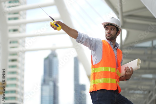 Architect or engineer with blueprints. Cauacsian Engineer checking plan on construction site. modern structure. helmet and blueprints paper.