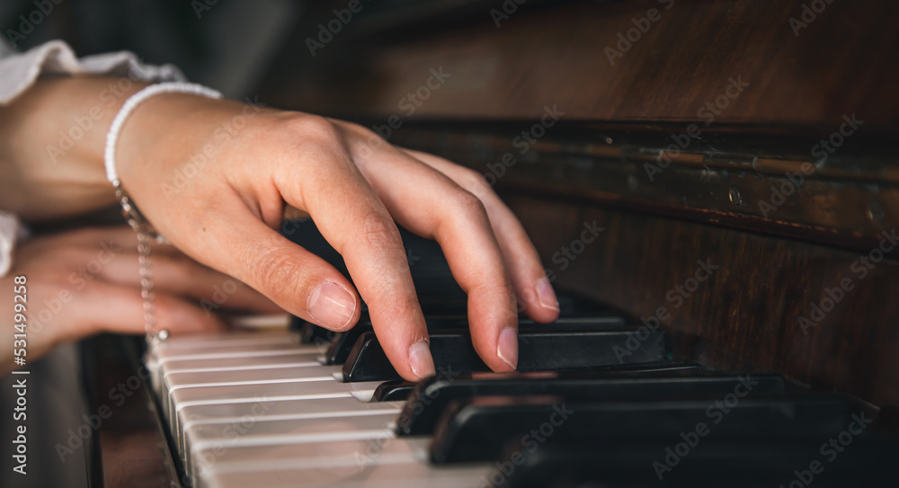 Fototapeta premium Female hands playing the old piano, close-up.