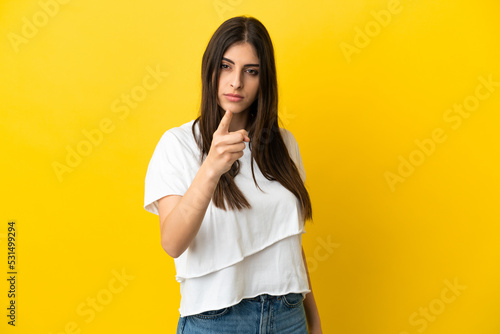 Young caucasian woman isolated on yellow background frustrated and pointing to the front © luismolinero