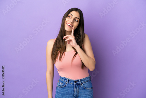 Young caucasian woman isolated on purple background thinking an idea while looking up